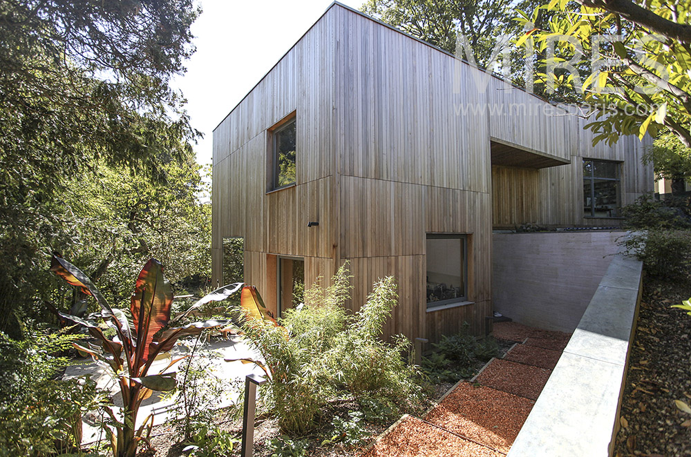 Maison de bois moderne entourée d’arbres. C1598
