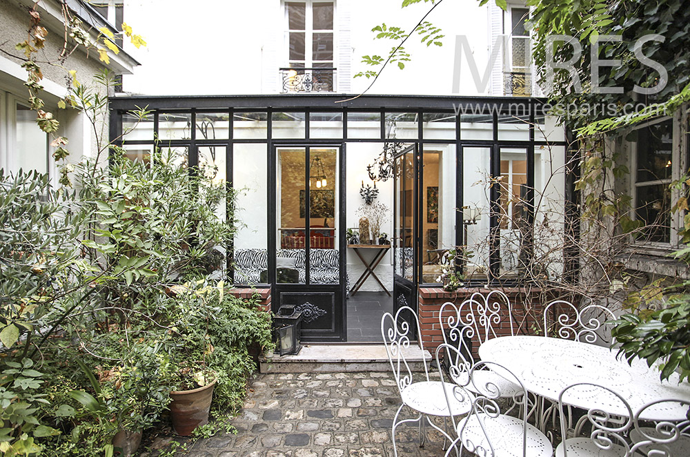 Veranda on paved courtyard and green plants. c1621