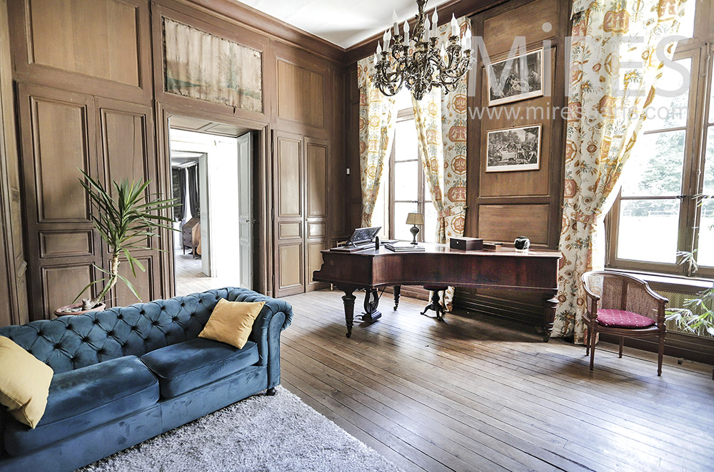 C1997 – Large living room with wood paneling and grand piano