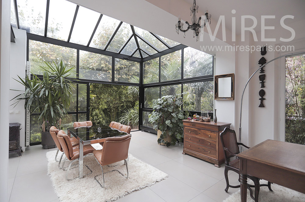 Dining room in glass roof, green plants. C2050